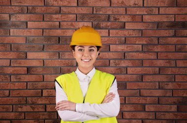 Tuğla duvar arka plan üzerinde üniformalı kadın endüstri mühendisi. Güvenlik ekipmanları