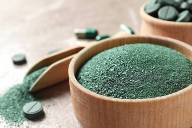 Ahşap kase ve tablo, closeup haplarla Spirulina tozu