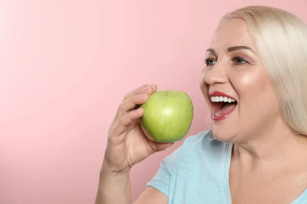 Mujer sonriente con dientes perfectos y manzana verde sobre fondo de color. Espacio para texto — Foto de Stock