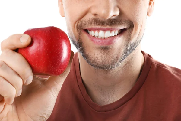 Uomo sorridente con denti perfetti e mela rossa su sfondo bianco, primo piano — Foto Stock