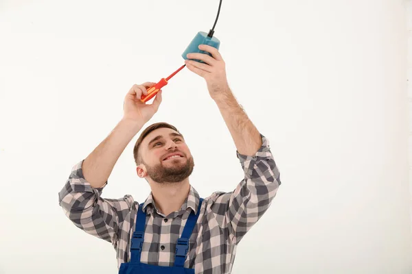 Elektriker med skruvmejsel reparera taklampa mot vit bakgrund — Stockfoto