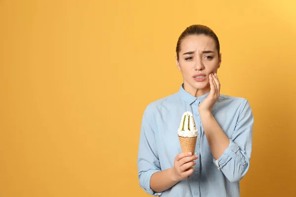 Emotionale junge Frau mit empfindlichen Zähnen und Eis auf farbigem Hintergrund. Raum für Text — Stockfoto