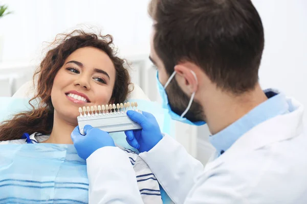 Tandläkare på patientens tänder färg med palett i office — Stockfoto