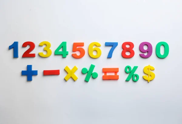 Барвисті магнітні номери та математичні символи на білому тлі, вид зверху — стокове фото