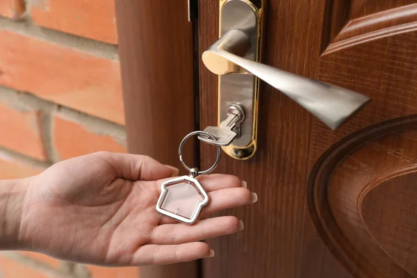 Femme tenant bibelot clé près de porte en bois, gros plan de la main — Photo