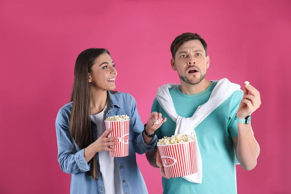 Emotionales Paar mit leckerem Popcorn auf farbigem Hintergrund — Stockfoto