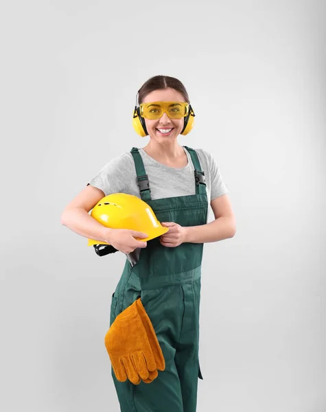 Female industrial worker in uniform on light background. Safety equipment — Stock Photo, Image