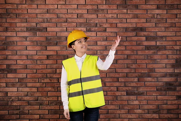 Ingeniera industrial femenina en uniforme sobre fondo de pared de ladrillo. Equipo de seguridad — Foto de Stock