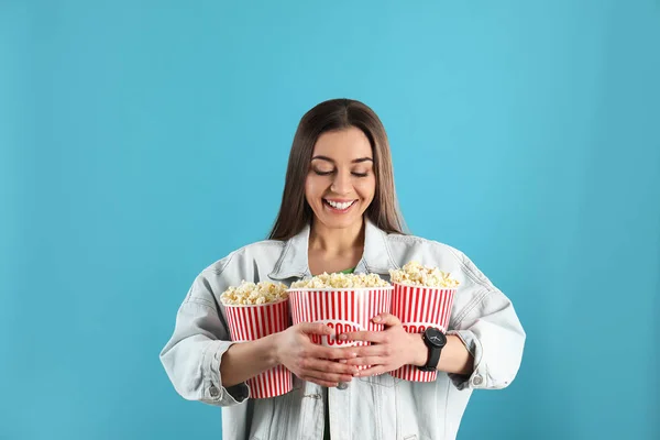 Junge Frau mit leckerem Popcorn auf farbigem Hintergrund — Stockfoto