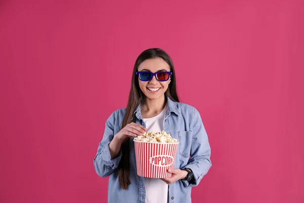 Young woman with 3D glasses and tasty popcorn on color background — Stock Photo, Image