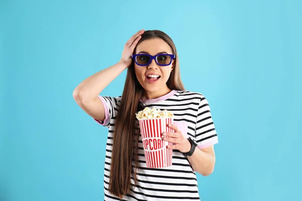 Emotional woman with 3D glasses and tasty popcorn on color background — Stock Photo, Image