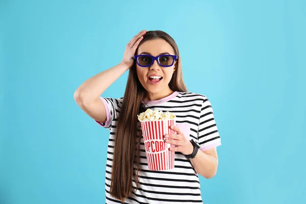 Mujer emocional con gafas 3D y palomitas de maíz sabrosas en el fondo de color —  Fotos de Stock