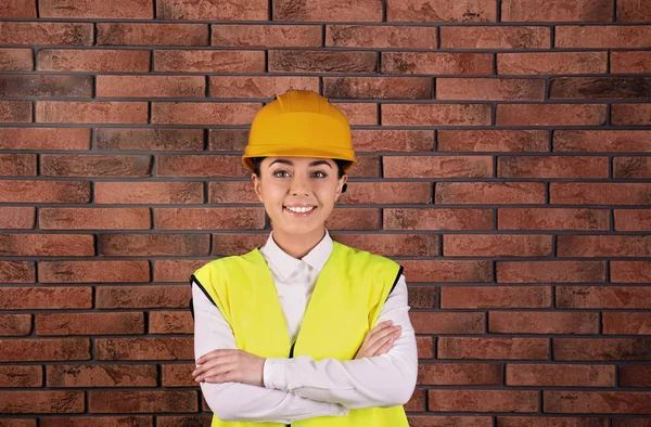Ingeniera industrial femenina en uniforme sobre fondo de pared de ladrillo. Equipo de seguridad — Foto de Stock