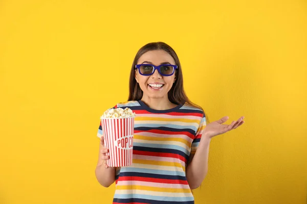 Mujer emocional con gafas 3D y palomitas de maíz sabrosas en el fondo de color — Foto de Stock