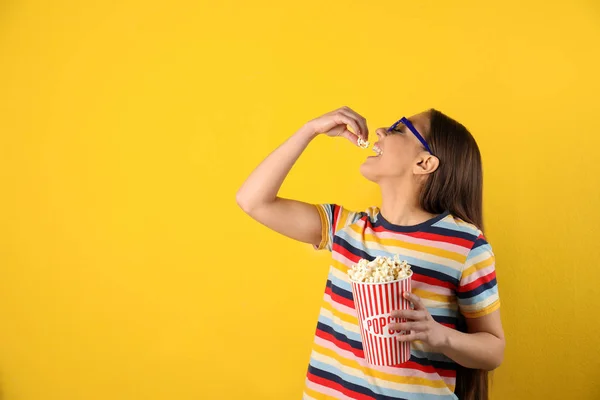 Junge Frau mit 3D-Brille, die leckeres Popcorn auf farbigem Hintergrund isst. Raum für Text — Stockfoto