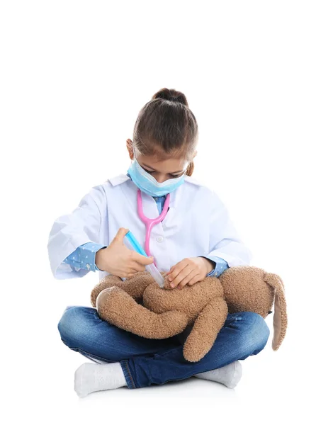 Bonito criança brincando médico com brinquedo de pelúcia no fundo branco — Fotografia de Stock