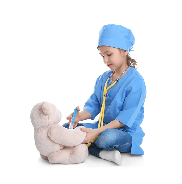 Bonito criança brincando médico com brinquedo de pelúcia no fundo branco — Fotografia de Stock