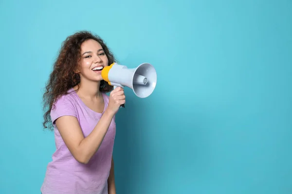 Joven mujer afroamericana con megáfono sobre fondo de color. Espacio para texto — Foto de Stock