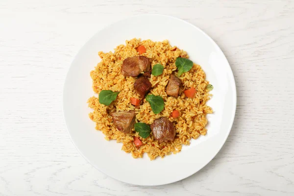 Placa con delicioso pilaf de arroz sobre fondo de madera, vista superior — Foto de Stock