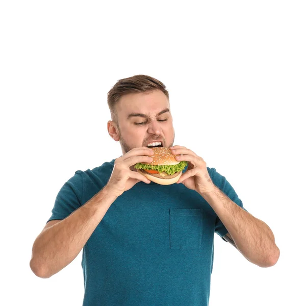 Jovem comendo hambúrguer saboroso no fundo branco — Fotografia de Stock