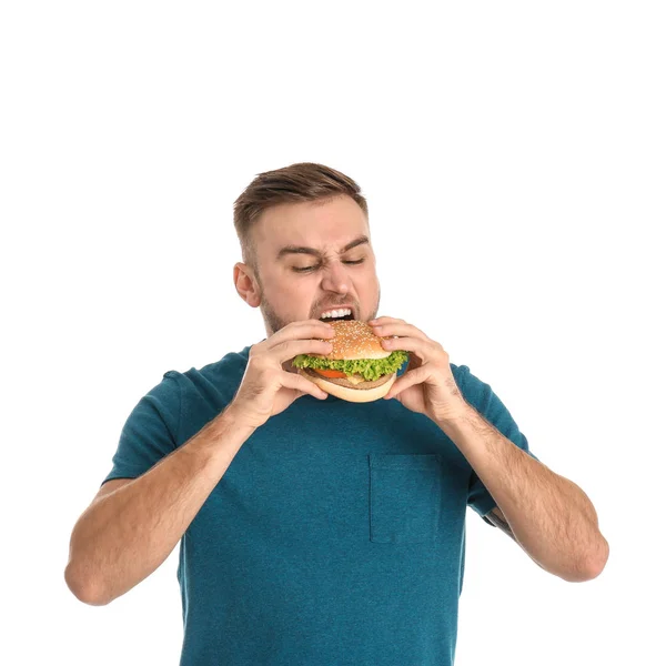 Jonge man eten smakelijke Hamburger op witte achtergrond — Stockfoto