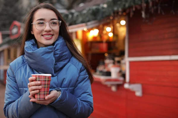 Жінка з чашкою глінтвейну на зимовому ярмарку. Простір для тексту — стокове фото