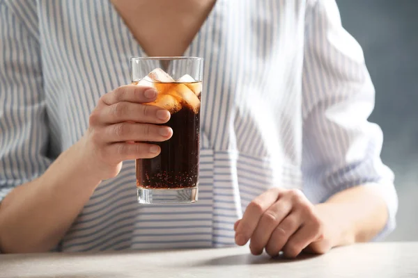 Femme avec verre de cola froid à table sur fond de couleur, gros plan — Photo