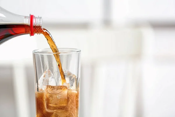 Menuang cola dari botol ke kaca pada latar belakang kabur, closeup. Ruang untuk teks — Stok Foto