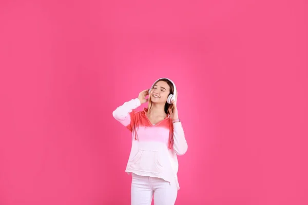 Девочка-подросток слушает музыку в наушниках на цветном фоне — стоковое фото