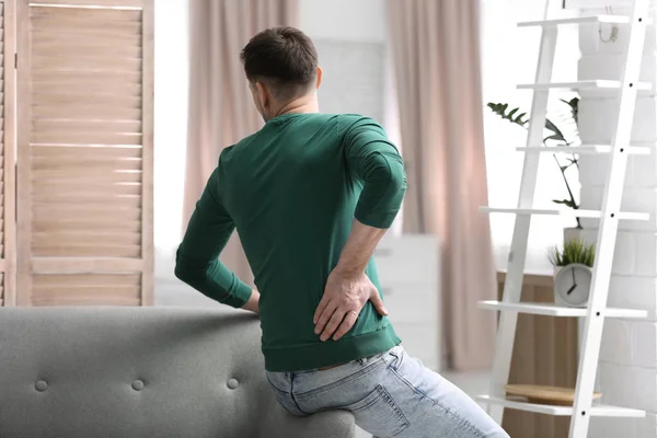 Young man suffering from back pain at home — Stock Photo, Image