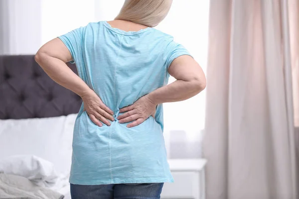 Senior mulher sofrendo de dor nas costas em casa, close-up — Fotografia de Stock