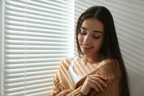 Mujer joven cerca de la ventana con persianas venecianas. Espacio para texto —  Fotos de Stock