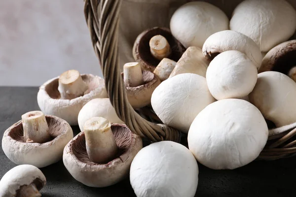 Champignons frais dispersés du panier sur la table, gros plan — Photo