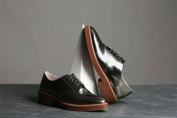 Composición con zapatos elegantes sobre mesa sobre fondo gris — Foto de Stock