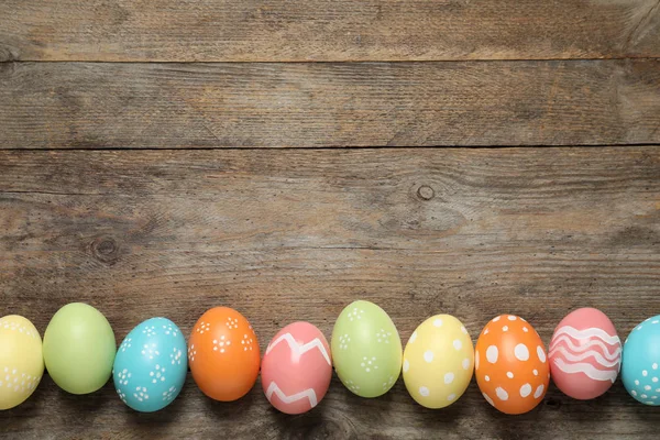 Composición plana de huevos de Pascua pintados sobre fondo de madera, espacio para texto —  Fotos de Stock
