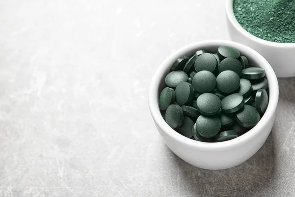 Kommen van spirulina pillen en poeder op een achtergrond met kleur, ruimte voor tekst — Stockfoto