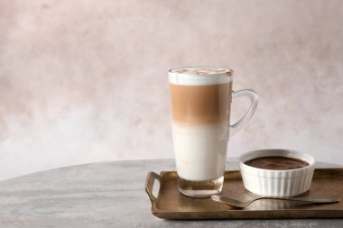 Karamel macchiato ve şurubu masada renk arka plan cam bardak ile tepsi. Metin için yer