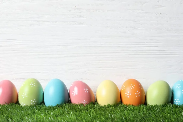 Coloridos huevos de Pascua pintados sobre hierba verde sobre fondo de madera, espacio para texto —  Fotos de Stock