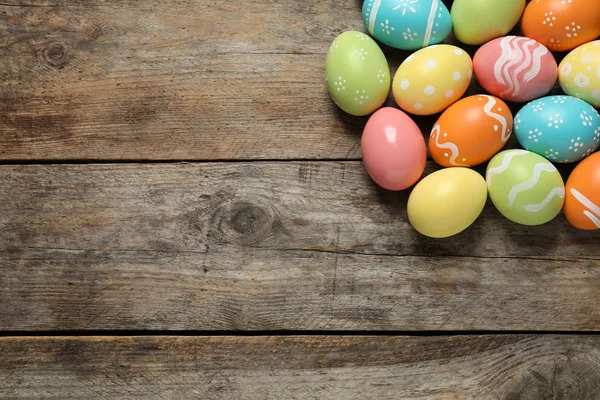 Muchos huevos de Pascua pintados de colores sobre fondo de madera, vista superior. Espacio para texto —  Fotos de Stock