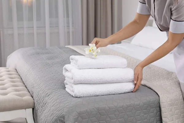 Υπηρέτρια, η τοποθέτηση των λουλουδιών σε νωπά πετσέτες στο δωμάτιο του ξενοδοχείου, κοντινό πλάνο — Φωτογραφία Αρχείου