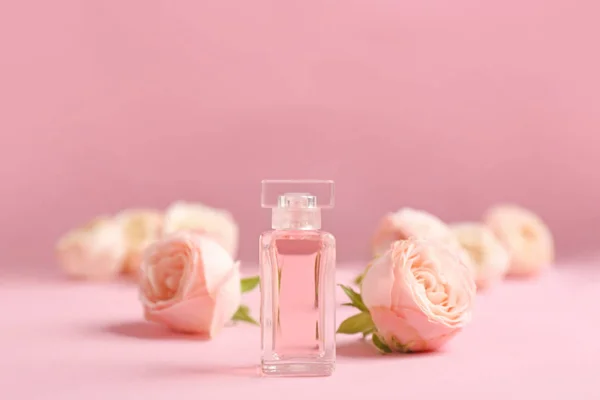 Bottiglia di profumo con belle rose su sfondo di colore — Foto Stock