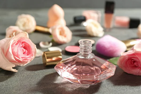 Schöne Komposition mit einer Flasche Parfüm und Rosen auf grauem Tisch — Stockfoto