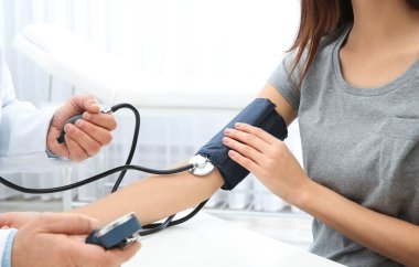 Genç kadın hastanede, closeup ziyaret doktor. Tansiyon ölçme ve nabız kontrol