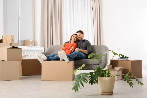 Пара отдыхает на диване рядом с передвижной коробкой в своем новом доме — стоковое фото
