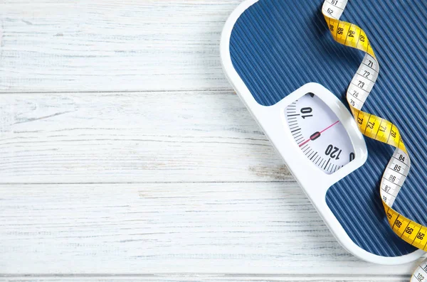 Scales and measuring tape on wooden background, top view with space for text. Weight loss — Stock Photo, Image