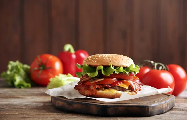 Hambúrguer saboroso com bacon na mesa de madeira. Espaço para texto — Fotografia de Stock