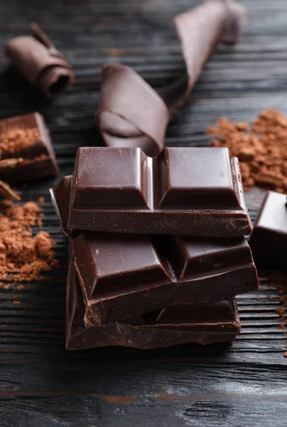 Pedaços de chocolate preto na mesa de madeira — Fotografia de Stock