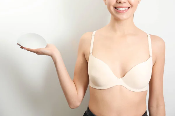 Mujer con implante de silicona para aumento de senos sobre fondo blanco, primer plano. Cirugía estética — Foto de Stock