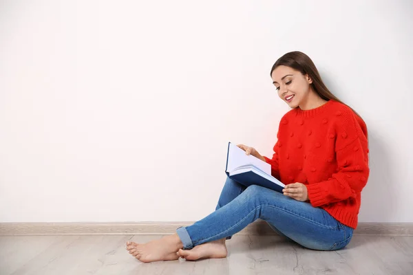 年轻女子在墙边地板上看书, 文字空间 — 图库照片