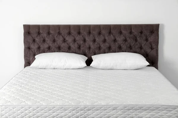 Άνετο κρεβάτι με καινούργιο στρώμα κοντά σε τοίχο στο δωμάτιο. Υγιή ύπνο — Φωτογραφία Αρχείου
